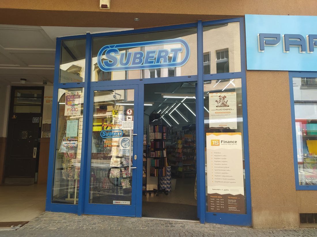Modrý prosklený vchod s nápisem Šubert a cedulí Papírnictví